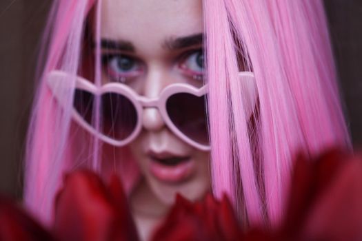 Surprised woman with tulip flowers - Pink hair and heart-shaped glasses - Out of focus, blurred background