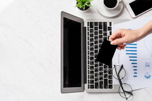 Concept of a woman is doing a online purchase, mock up card and cellphone on office desk isolated on beautiful fashion marble background, copy space, top view, flat lay, closeup