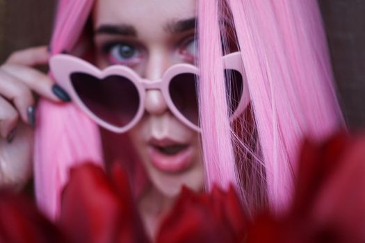 Surprised woman with tulip flowers - Pink hair and heart-shaped glasses - Out of focus, blurred background