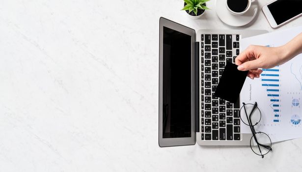 Concept of a woman is doing a online purchase, mock up card and cellphone on office desk isolated on beautiful fashion marble background, copy space, top view, flat lay, closeup