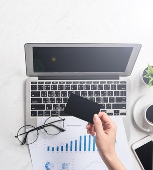 Concept of a woman is doing a online purchase, mock up card and cellphone on office desk isolated on beautiful fashion marble background, copy space, top view, flat lay, closeup