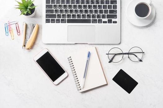 Stylized clean marble office working desk with smartphone, laptop, glasses and coffee, workspace design, mock up, top view, flat lay, copy space, closeup