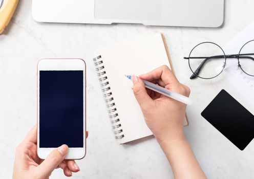Concept of a woman is doing a accounting, mock up card and cellphone on office desk isolated on beautiful fashion marble background, copy space, top view, flat lay, closeup