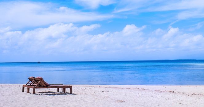 Chairs on the amazing beautiful sandy beach near the ocean with blue sky. Concept of summer leisure calm vacation for a tourism idea. Empty copy space, inspiration of tropical landscape