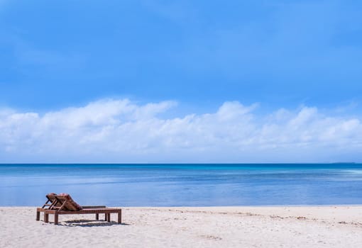Chairs on the amazing beautiful sandy beach near the ocean with blue sky. Concept of summer leisure calm vacation for a tourism idea. Empty copy space, inspiration of tropical landscape