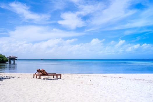 Chairs on the amazing beautiful sandy beach near the ocean with blue sky. Concept of summer leisure calm vacation for a tourism idea. Empty copy space, inspiration of tropical landscape