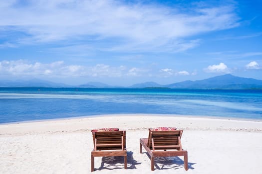 Chairs on the amazing beautiful sandy beach near the ocean with blue sky. Concept of summer leisure calm vacation for a tourism idea. Empty copy space, inspiration of tropical landscape