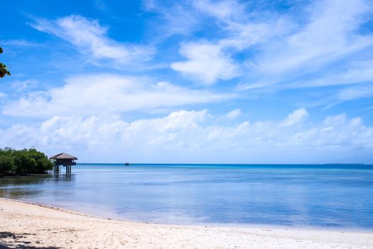 Beautiful amazing gold colored sandy beach with soft waves isolated with sunny blue sky. Concept of tropical calm tourism idea, copy space, close up