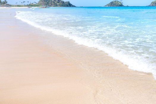 Beautiful amazing gold colored sandy beach with soft waves isolated with sunny blue sky. Concept of tropical calm tourism idea, copy space, close up
