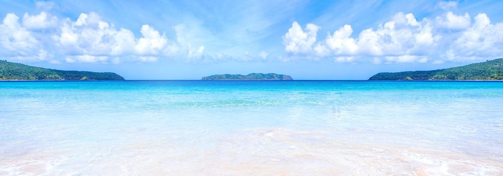 Beautiful amazing gold colored sandy beach with soft waves isolated with sunny blue sky. Concept of tropical calm tourism idea, copy space, close up
