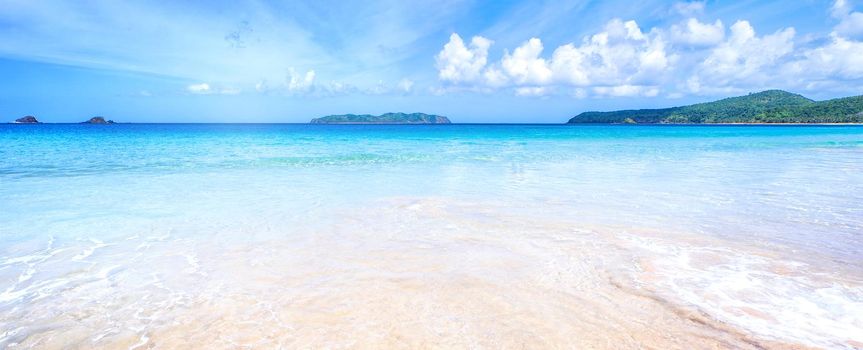 Beautiful amazing gold colored sandy beach with soft waves isolated with sunny blue sky. Concept of tropical calm tourism idea, copy space, close up