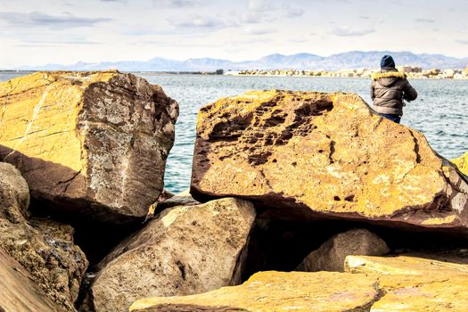 Man Fishing and relaxing in the dock in a sunny day in Santa Pola, Alicante, Spain