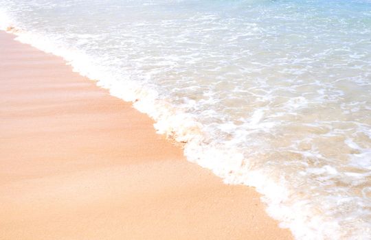 Beautiful amazing gold colored sandy beach with soft waves isolated with sunny blue sky. Concept of tropical calm tourism idea, copy space, close up