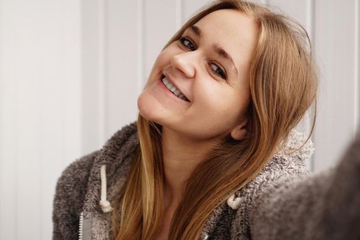 Picture of young happy emotional pretty lady indoors. Looking camera make selfie