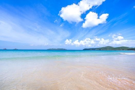 Beautiful amazing gold colored sandy beach with soft waves isolated with sunny blue sky. Concept of tropical calm tourism idea, copy space, close up