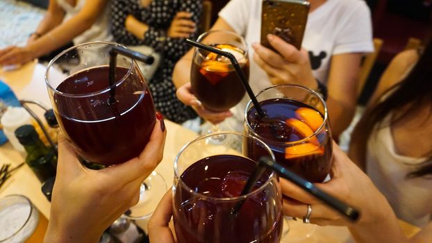 People drink a cocktail. Alcohol. Club. Cheerful company in the bar holds glasses with red sangria. Holiday in spain concept