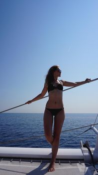 Attractive girl in a black bathing suit on a yacht at summer day. coast of barcelona