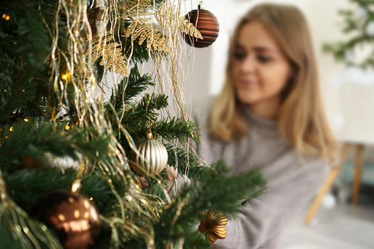 Beautiful young woman decorating a Christmas tree - soft colors. Blurred background