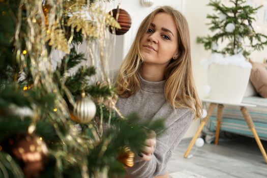 Beautiful young woman decorating a Christmas tree - soft colors