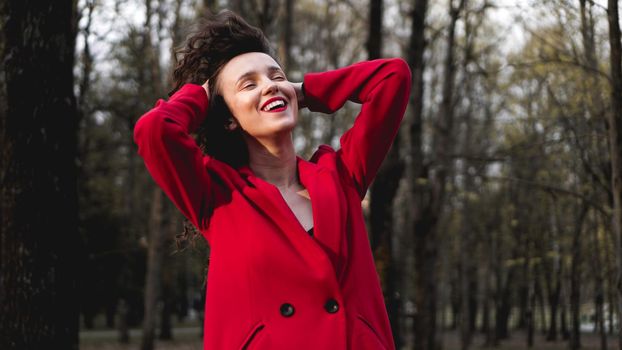 Glamorous woman wearing red outfit and matching red lip gloss. Portrait in the park