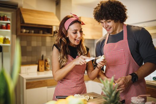 A cheerful couple cooking in the kitchen together.