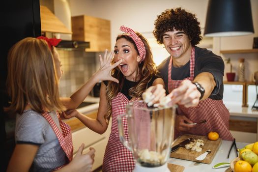 A cheerful parents spending quality time in kitchen at home with theirs cute daughter.