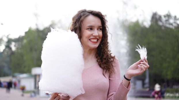 Close up portrait of a happy smiling excited girl holding cotton candy at amusement park