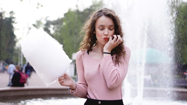 Close up portrait of a happy smiling excited girl holding cotton candy at amusement park