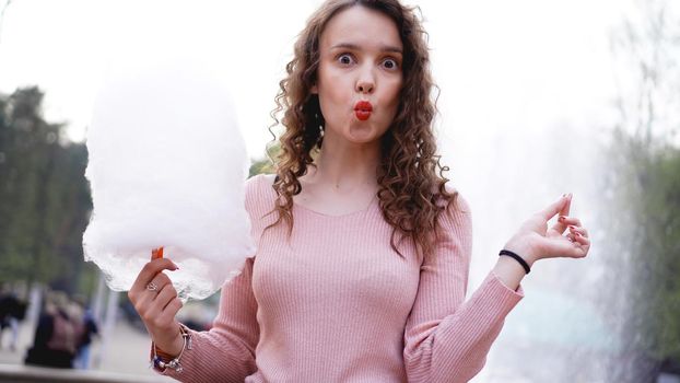 Close up portrait of a happy smiling excited girl holding cotton candy at amusement park