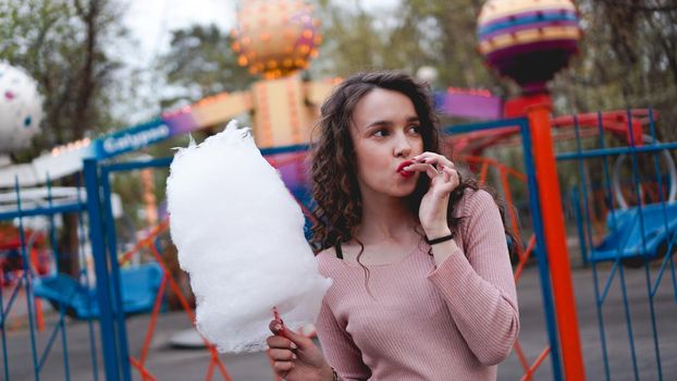 Close up portrait of a happy smiling excited girl holding cotton candy at amusement park