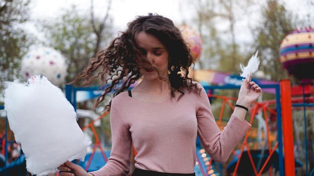 Close up portrait of a happy smiling excited girl holding cotton candy at amusement park