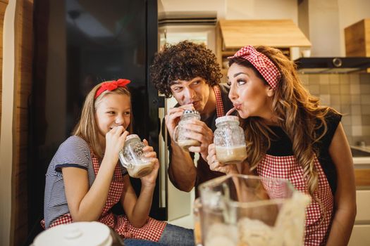 A cheerful parents and their young daughter trying a new recipe in the kitchen together.