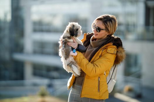 Portrait of a smiling woman holding her cute small Shih Tzu dog outdoor.