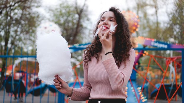 Close up portrait of a happy smiling excited girl holding cotton candy at amusement park