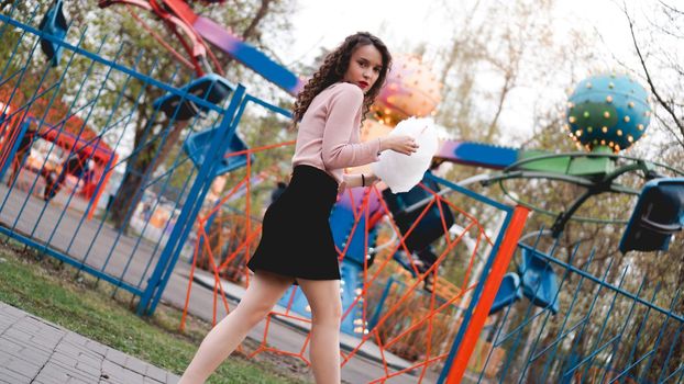 Close up portrait of a happy smiling excited girl holding cotton candy at amusement park