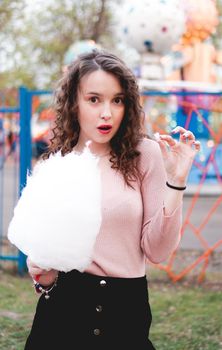 Close up portrait of a happy smiling excited girl holding cotton candy at amusement park