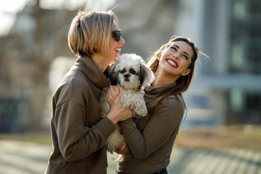 Portrait of a two young female friends with their pet Shih Tzu dog at the city.
