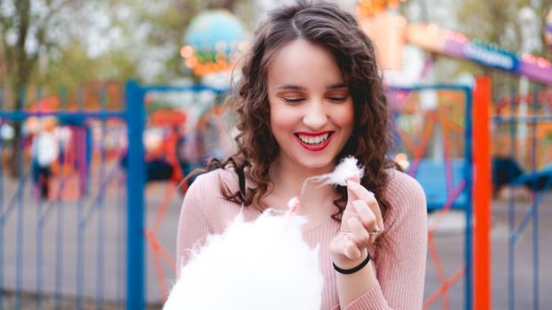 Close up portrait of a happy smiling excited girl holding cotton candy at amusement park