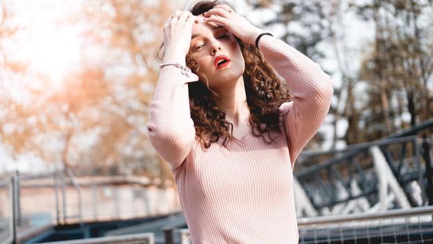 Closeup of a beautiful young woman with curly hair - a sunset behind her