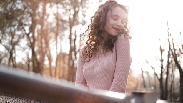 Closeup of a beautiful young woman with curly hair - a sunset behind her