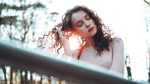 Closeup of a beautiful young woman with curly hair - a sunset behind her