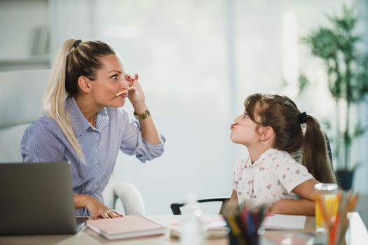 A single mother making fun with her daughter while she does her homework.