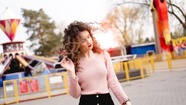 Beautiful exited smiling woman having fun and dancing at amusement park at hot summer