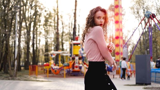 Beautiful exited smiling woman having fun and dancing at amusement park at hot summer