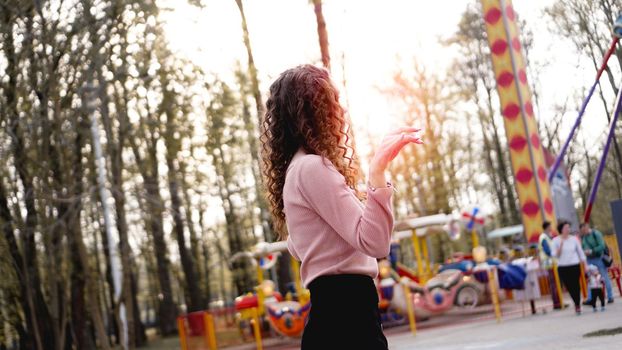 Beautiful exited smiling woman having fun and dancing at amusement park at hot summer