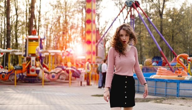 Beautiful exited smiling woman having fun and dancing at amusement park at hot summer