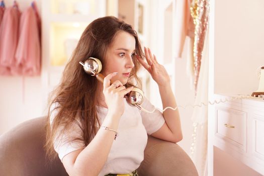 A surprised woman talks on the phone. phone handset in retro style. The girl in the dressing room in pink color