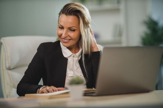 A confident attractive business woman sitting at her office desk and working.