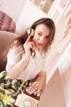 A woman talks on the phone. phone handset in retro style. The girl in the dressing room in pink color