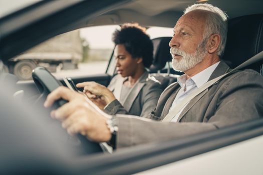 Shot of a successful senior business man during morning commute with his black female coworker.